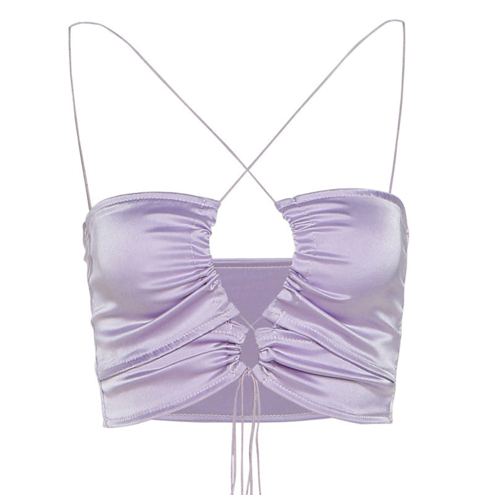 Front view of a shiny lilac satin crop top with thin spaghetti straps that cross at the back, featuring a bold front keyhole cutout, ruched detailing, and adjustable tie closures at the hem.