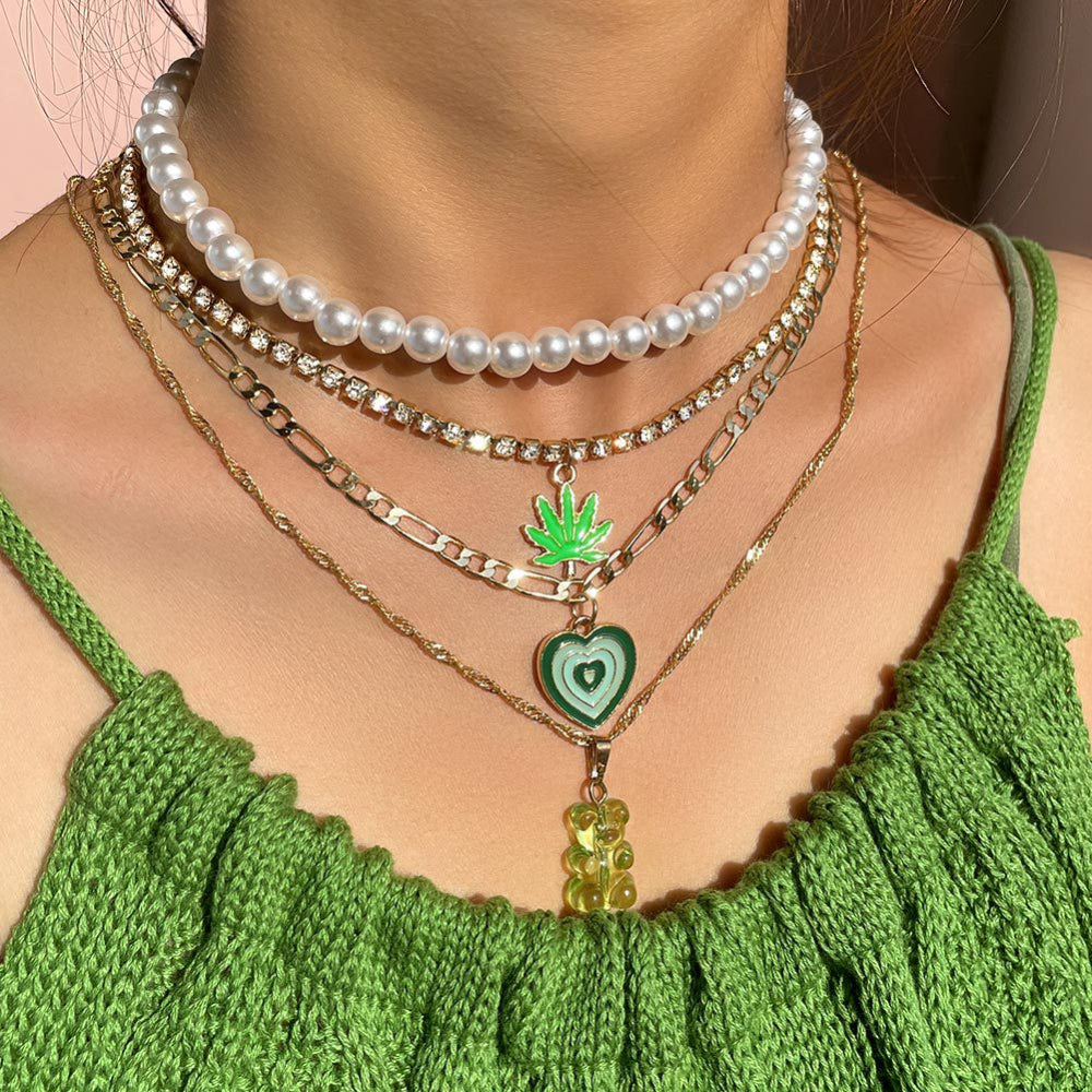 Gold pearl layered necklace set with green heart, leaf & gummy bear pendants – trendy statement jewelry collection on a model