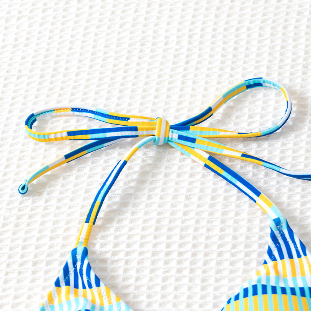 Blue and yellow striped bikini top on a textured white background