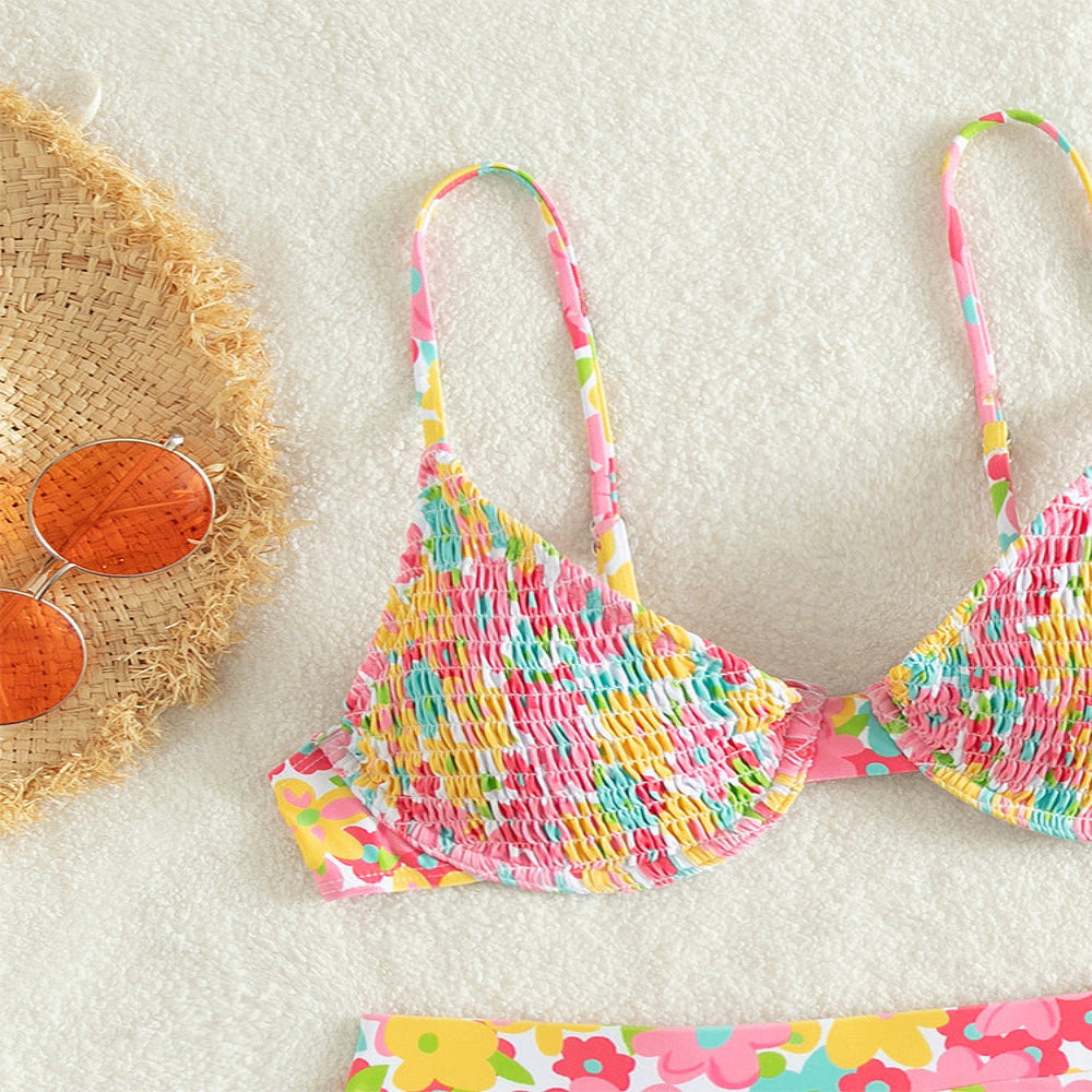 Colorful bikini set on a white background with sunglasses and a hat.