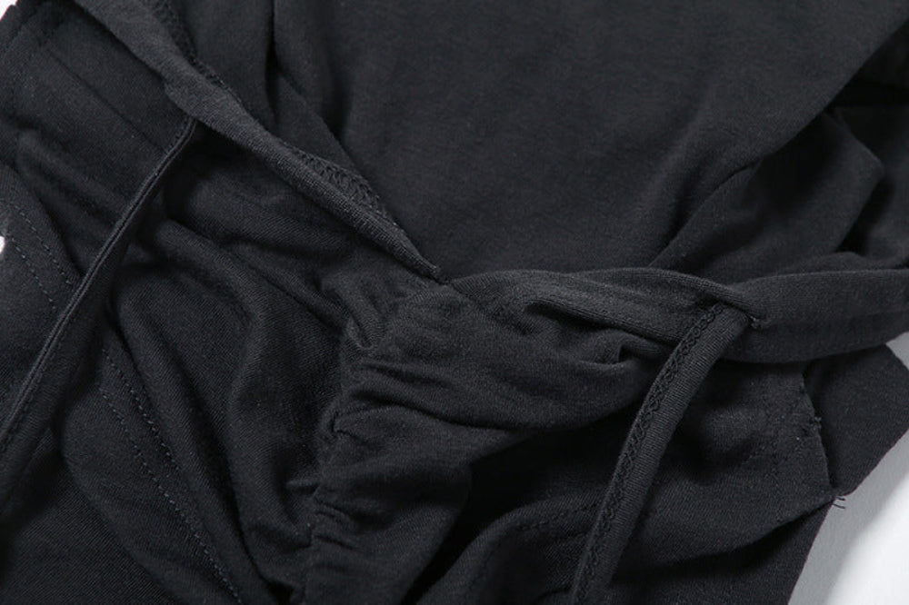 Close-up detail of black fabric on a hooded crop top, showcasing twisted and ruched construction with visible stitching and adjustable ties at the front.