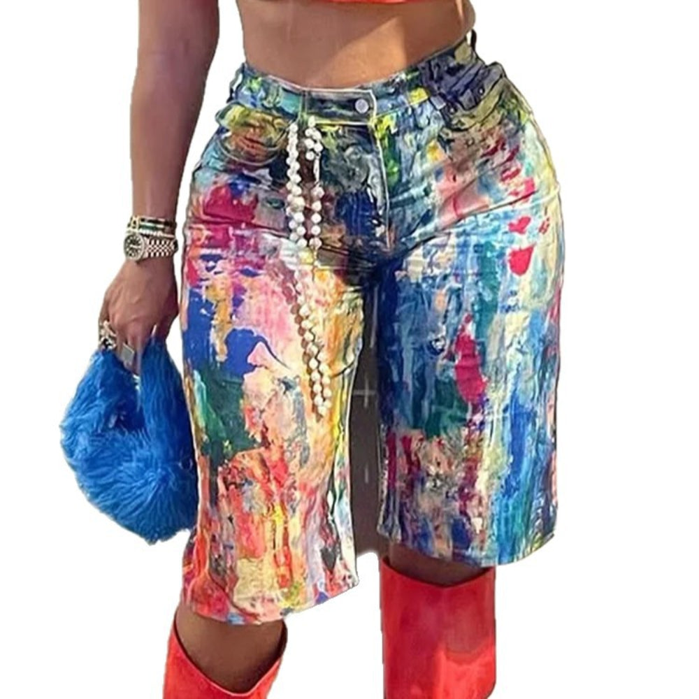 Close-up view of colorful paint-splatter denim cargo shorts with pearl chain accessory, styled with red knee-high boots and a bright blue furry handbag. Vibrant street-style fashion detail for Boutique Jolie.