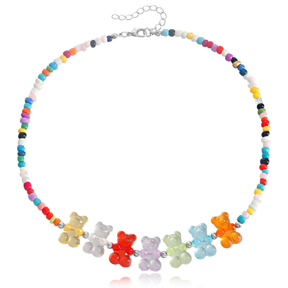 Rainbow beaded choker necklace with multicolored seed beads and seven vibrant translucent gummy bear charms in yellow, clear, red, purple, green, blue, and orange. Delicate fun statement piece with silver clasp and extender chain, displayed on a clean white background.