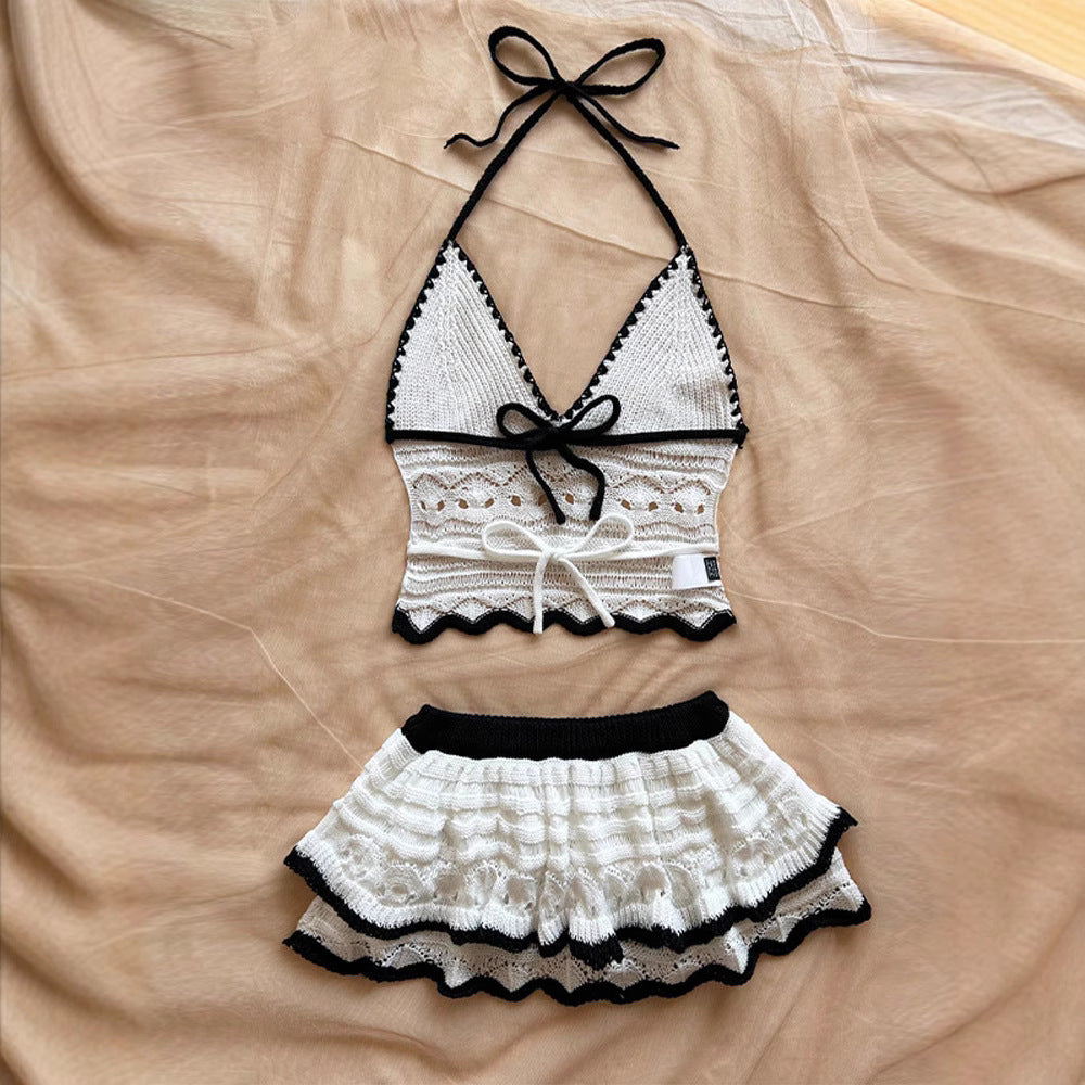 White and black crochet halter crop top with tie details and matching ruffled mini skirt set laid flat