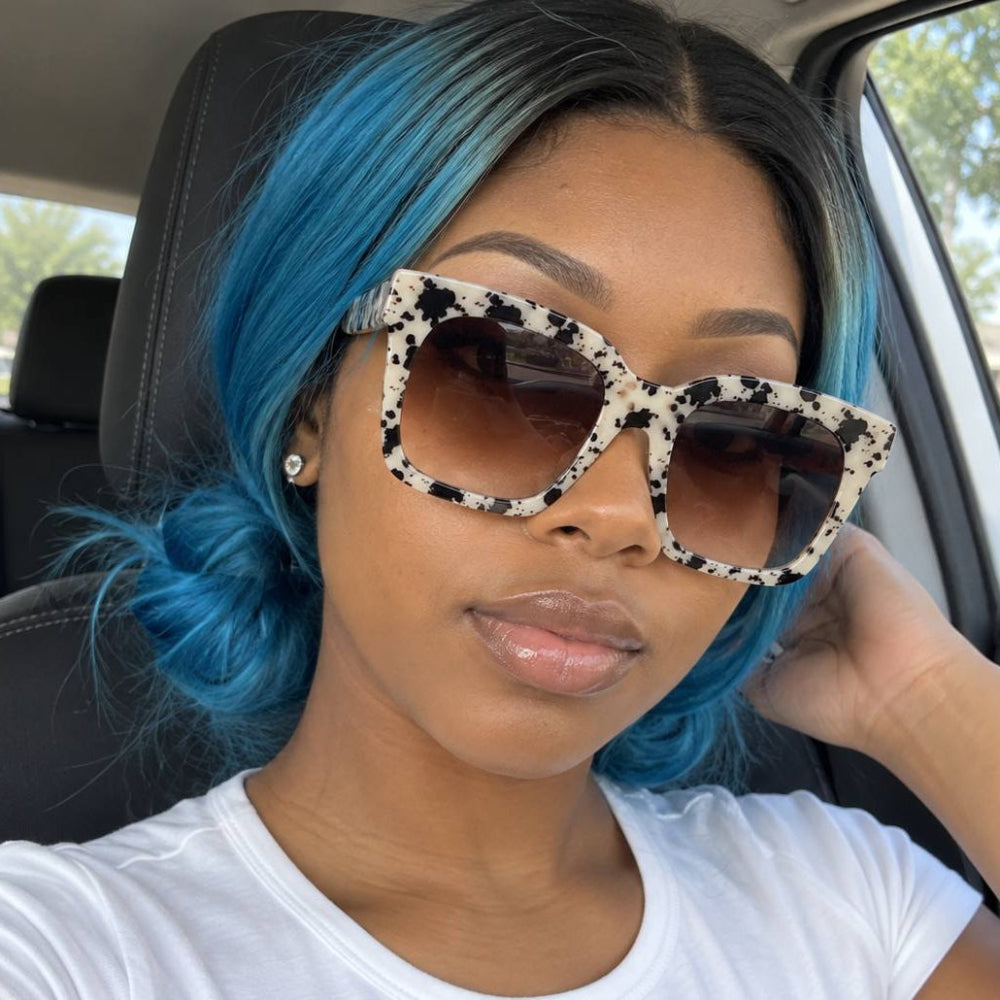 Woman with blue hair wearing black-and-white speckled square Rivet Big-Frame Pop Sunglasses.