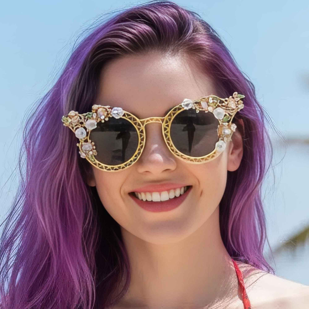 Gold floral jeweled sunglasses on purple hair model – trendy ornate statement sunnies with butterfly details, beach fashion close-up.