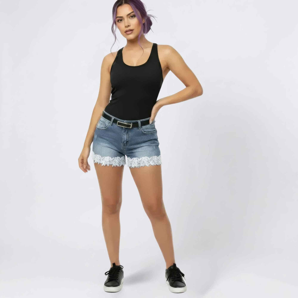 Woman with purple hair modeling black tank top and blue denim shorts with delicate white lace trim at the hem, styled with a black belt and black sneakers. Studio product photography for Boutique Jolie fashion collection