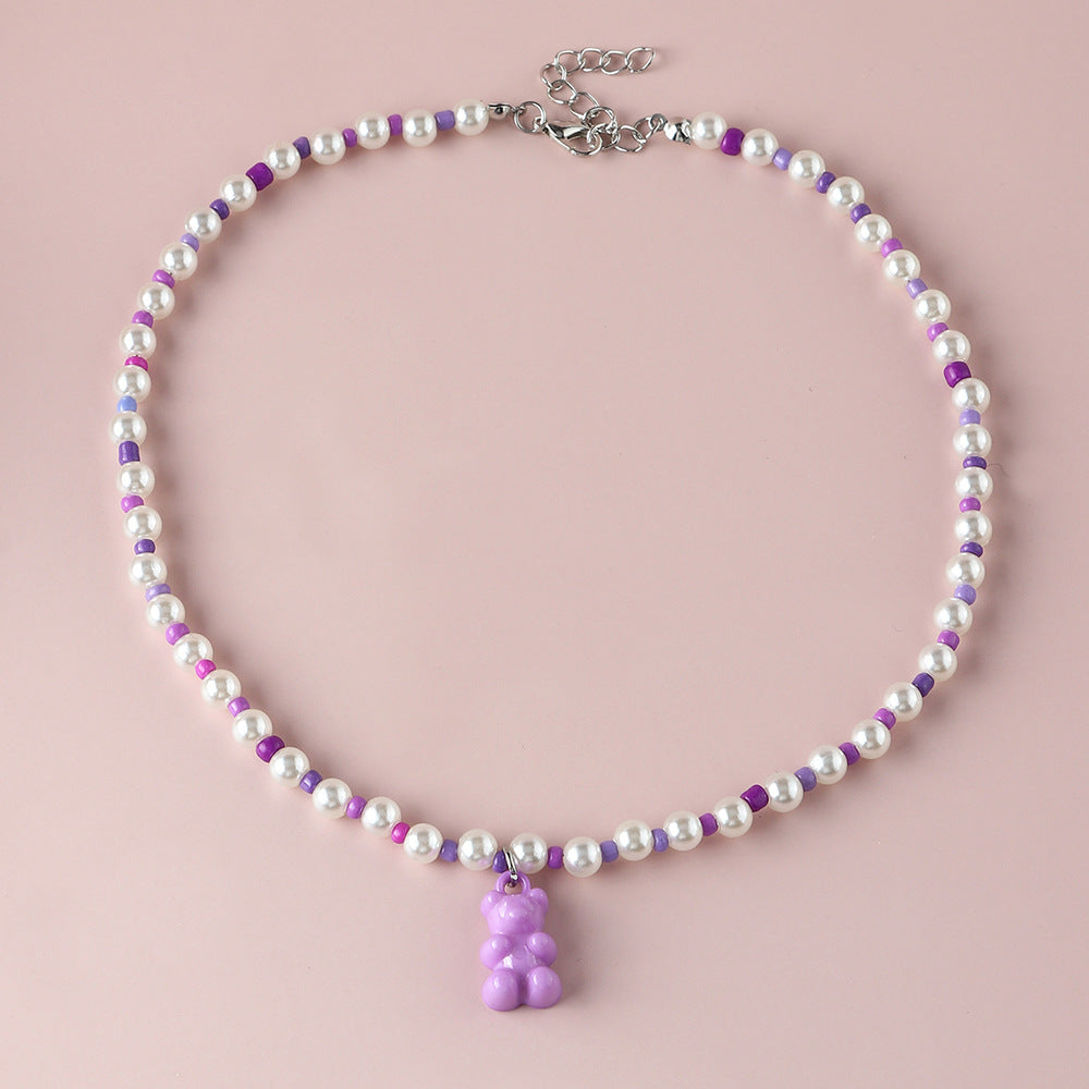 White pearl purple gummy bear necklace – trendy colorful beaded choker with fun bear pendant, studio pink background.