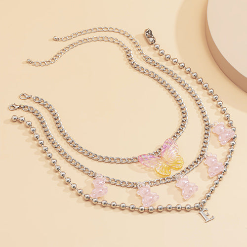 Silver butterfly and flower charm necklace with initial pendant – trendy layered beaded jewelry, statement accessory flat lay.