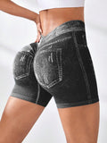Woman modeling black denim-style high-waisted stretch shorts with white contrast stitching and back pockets, shown from a rear three-quarter view while adjusting the waistband against a clean white studio background.