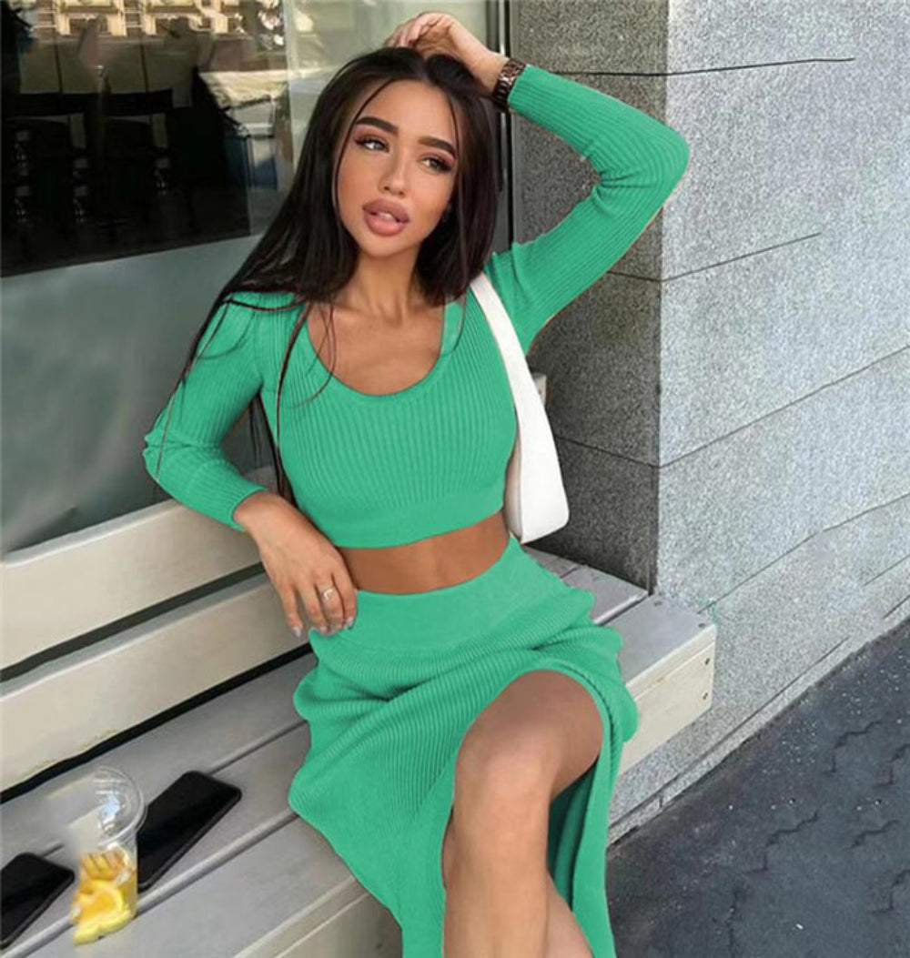 Woman in bright green ribbed long-sleeve crop top and high-slit midi skirt set, seated on bench outdoors.