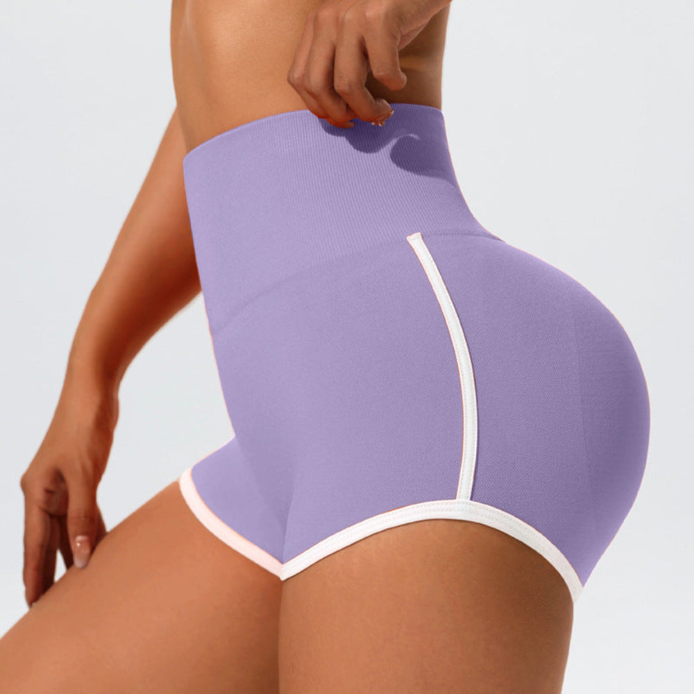 Woman modeling purple high-waisted bikini bottoms with white contrast trim, shown from a rear three-quarter view against a light studio background.