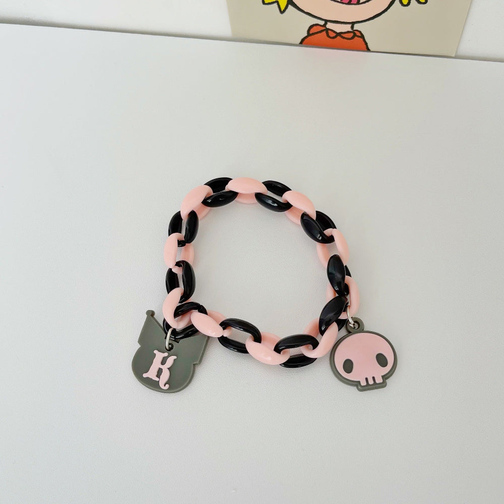 Pastel pink and black link chain bracelet featuring a gray cat-shaped charm with the letter "K" and a cute pink skull charm