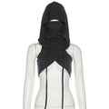 Black hooded crop top on a mannequin with a full head-covering balaclava-style hood, face opening, draped and twisted fabric at the chest, and long adjustable ties hanging down the front.