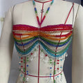 Mannequin displaying a vibrant rainbow beaded halter crop top featuring multiple layers of colorful beads in red, orange, yellow, green, blue, and purple. Includes cascading fringe with dangling crystal charms and beaded straps.