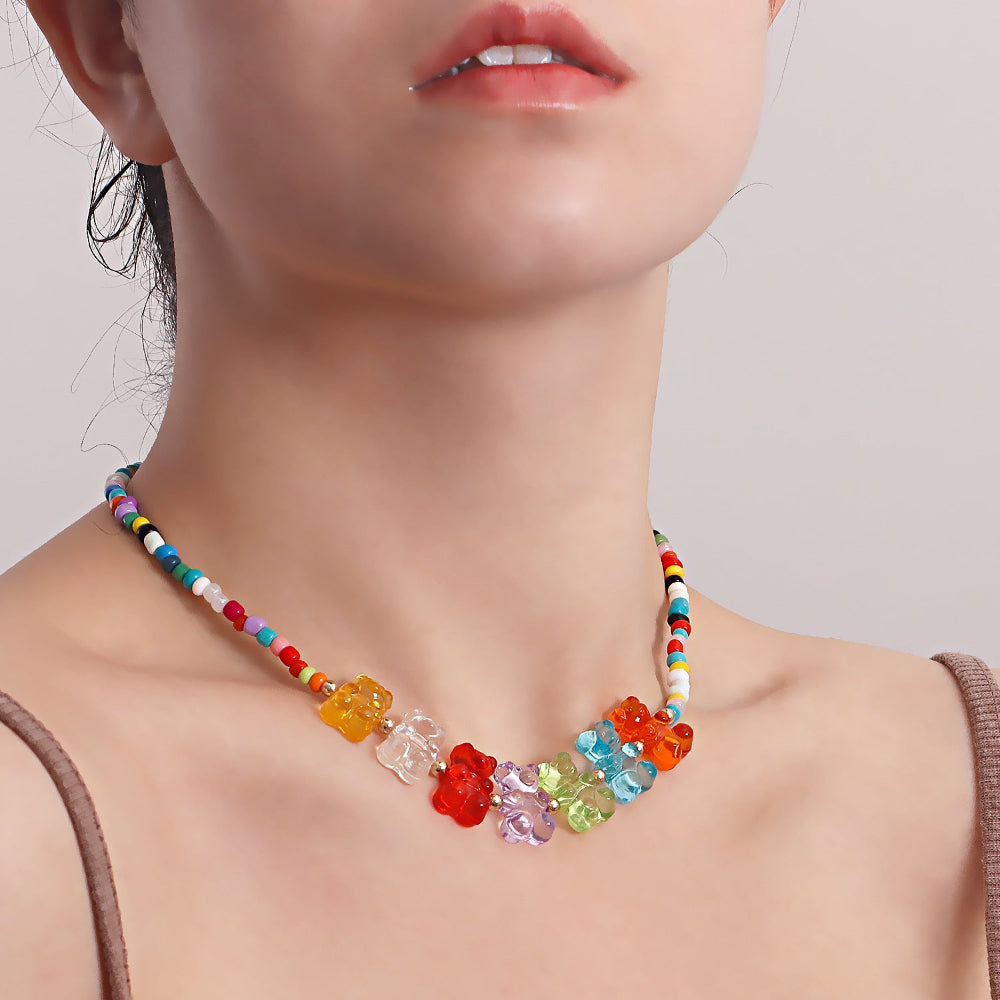 Colorful beaded necklace with multicolored seed beads and a row of vibrant translucent gummy bear charms in rainbow shades (red, orange, yellow, clear, purple, green, blue). Highlighting its fun and playful summer-ready design.