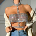 Woman wearing a dazzling multicolored iridescent rhinestone crop top with high choker neck, halter strap, and sparkling sequin embellishments. Styled with an open white blazer and blue jeans, showcasing the intricate crystal details.