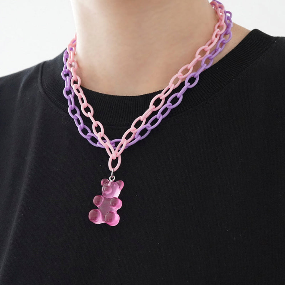 Layered pastel pink and purple oversized chain necklace featuring a translucent pink gummy bear charm pendant, worn on model