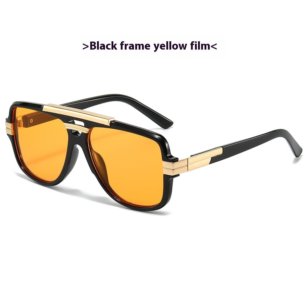 Black square retro sunglasses with gold brow bar and yellow-orange lenses, product photo on a white background.