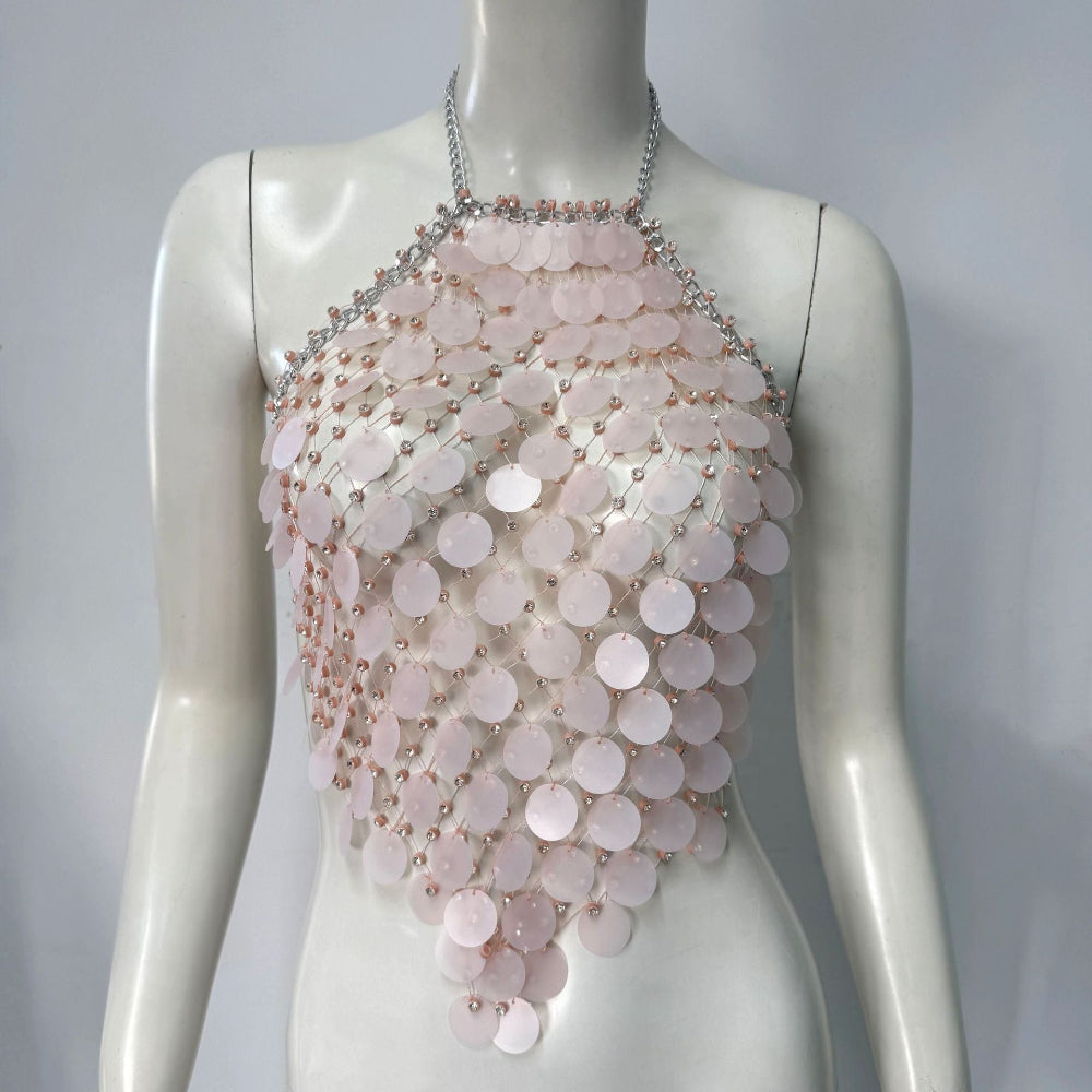 Mannequin wearing a luxurious pale pink sequin halter top featuring cascading iridescent circular sequins, silver chain straps, and delicate bead accents. The statement piece has a flowing, layered design with sparkling details.