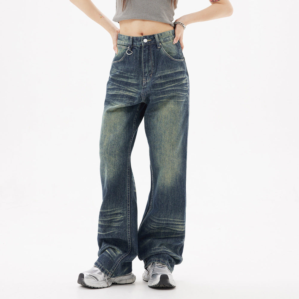 Woman modeling dark blue wide-leg baggy jeans with faded wash and front pockets, paired with a grey crop top and chunky sneakers. Full-body casual street-style fashion shot for Boutique Jolie.