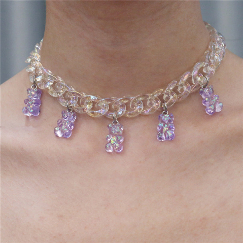 Iridescent clear chunky chain choker necklace with sparkling translucent purple gummy bear charms. Bold, playful statement piece shown worn on a model, featuring holographic acrylic links and dangling bear pendants.