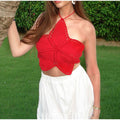 Model wearing a red crochet halter crop top with intricate floral butterfly design, paired with a white skirt.