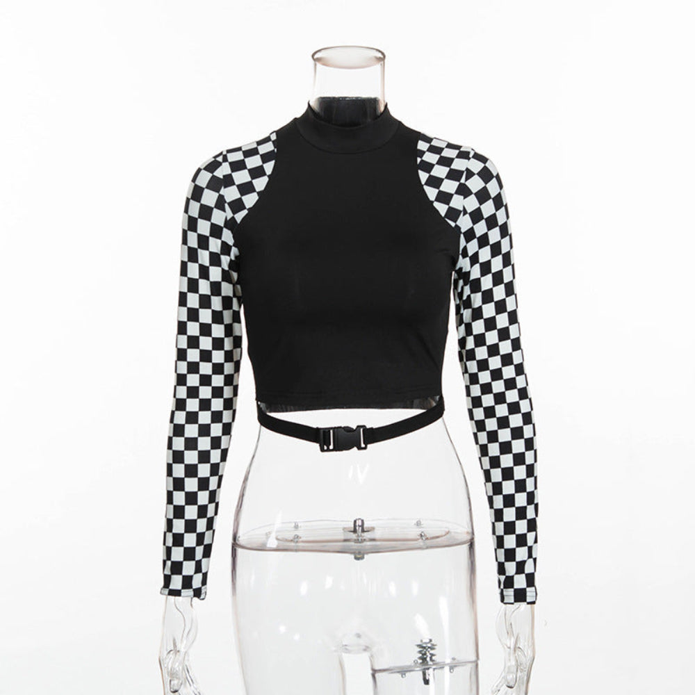 Front view of a black long-sleeve crop top on a transparent mannequin. The top features a solid black body, high mock neck, and bold black-and-white checkerboard pattern on the sleeves, styled with a black waist belt.
