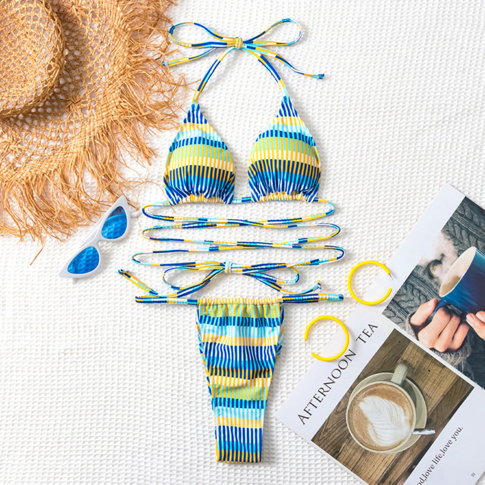 Striped bikini set with sunglasses, hat, and magazine on a textured surface