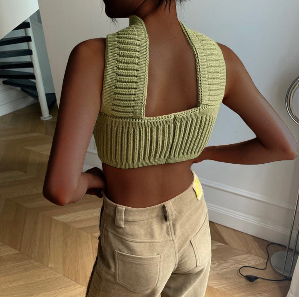 Back view of model wearing a lime green ribbed knit crop top with high turtleneck collar, open back design, and sleeveless style, paired with beige cargo pants.