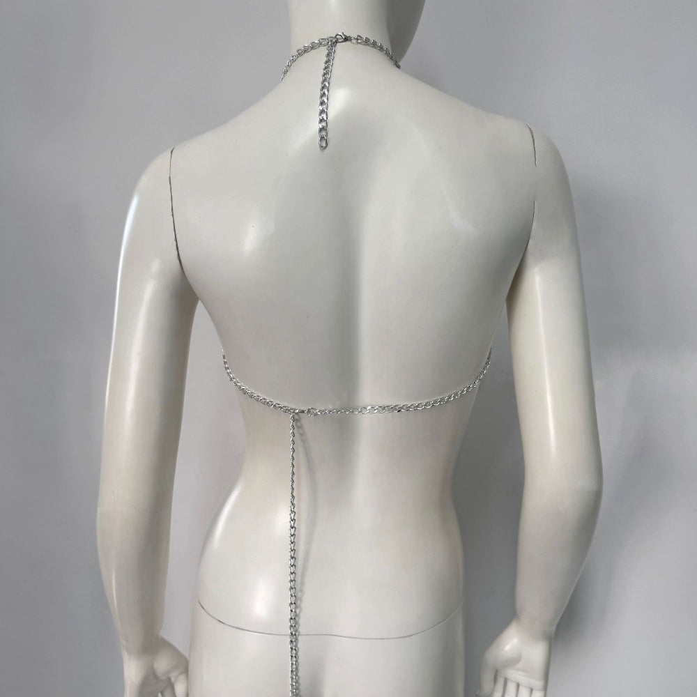 Back view of a white mannequin displaying a silver chain body harness featuring a halter neck chain with dangling detail and a lower back chain band with a long vertical tassel chain.