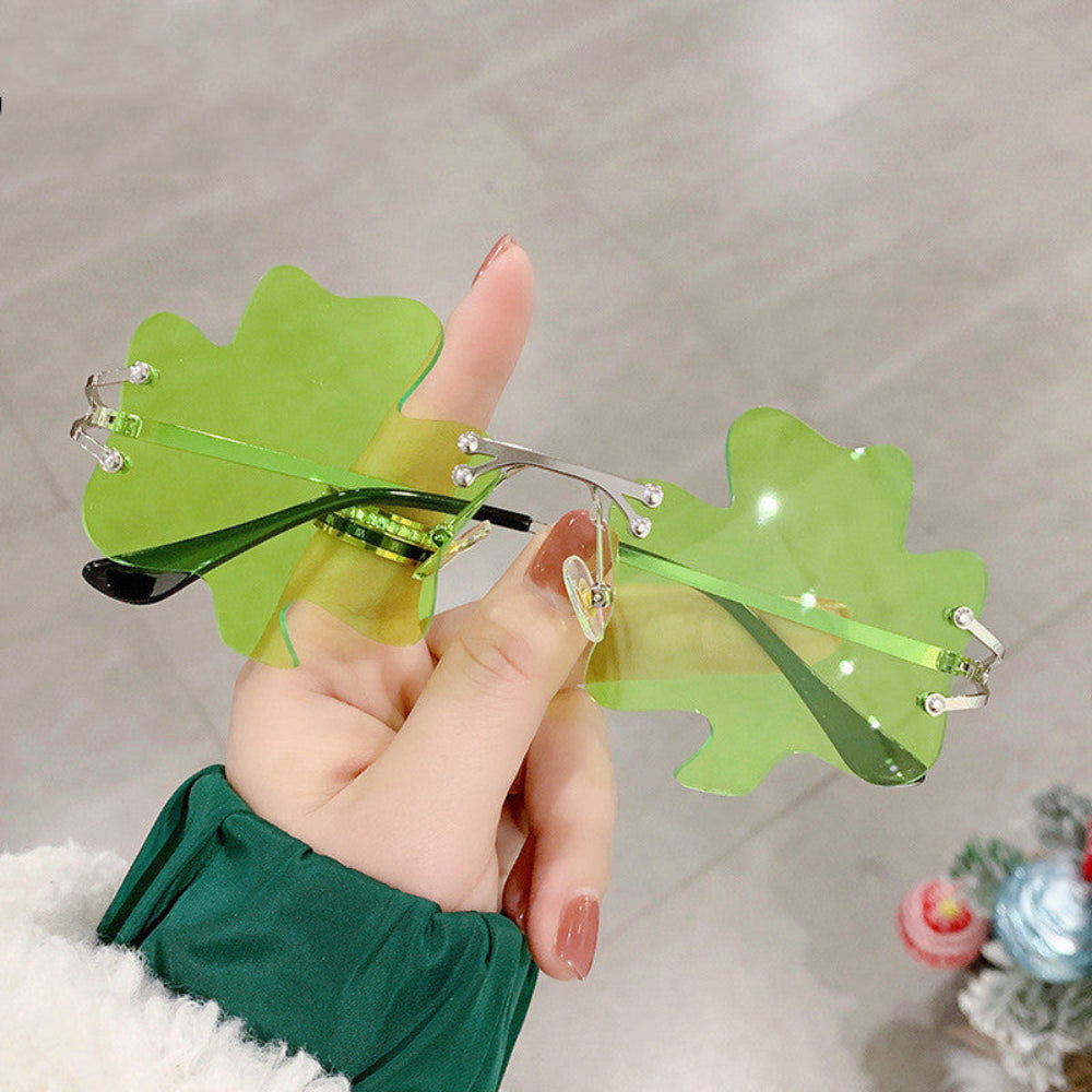 Hand holding rimless light-green shamrock sunglasses with silver frames.