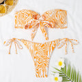 Orange and white patterned bikini set on a white background with sunglasses and flowers.
