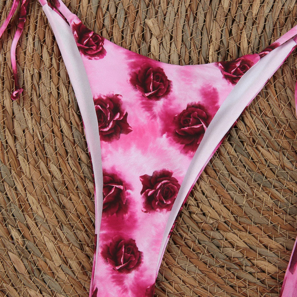 Pink bikini bottom with red rose pattern on a woven surface