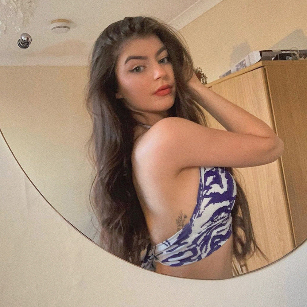 Woman in a blue and white patterned bikini standing in front of a mirror.