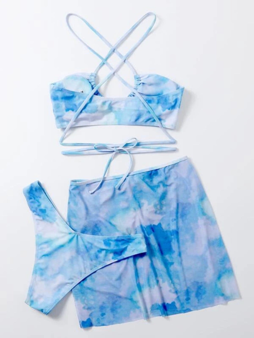Blue tie-dye three-piece swimwear set with bandeau bikini top, crisscross back straps, matching bikini bottom and ruched mini skirt with tie waist.